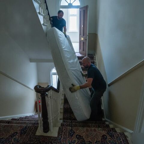 Workers carrying mattress down narrow stairwell in Tunbridge Wells flat