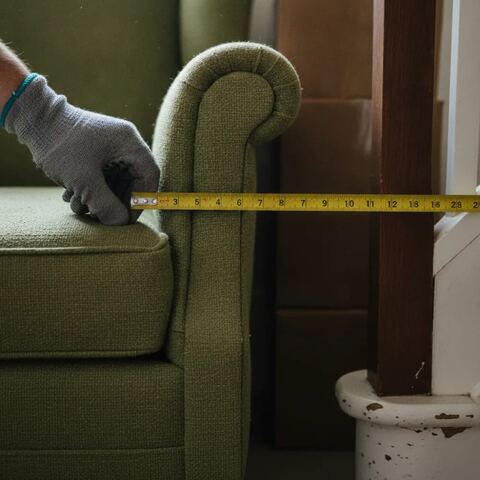 Hands measuring armchair before furniture removal in narrow Tunbridge Wells staircase