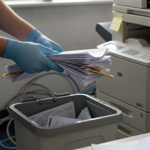 Hands sorting confidential paperwork into secure bin during office clearance Tunbridge Wells